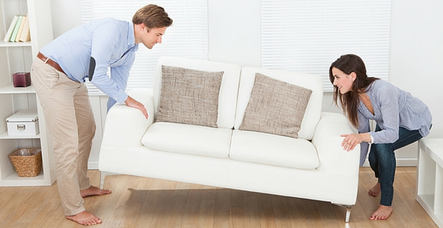 couple lifts a love seat together preparing for a flooring installation